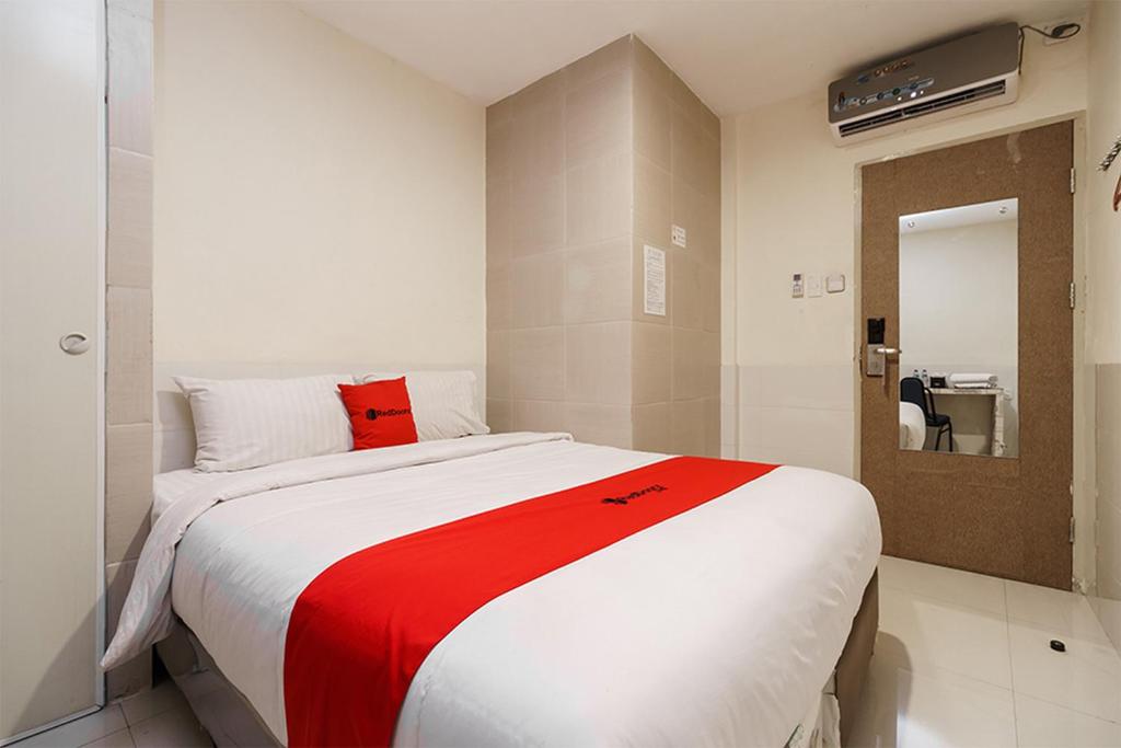 棉兰Permata Inn的一间卧室配有一张带红色毯子的大床