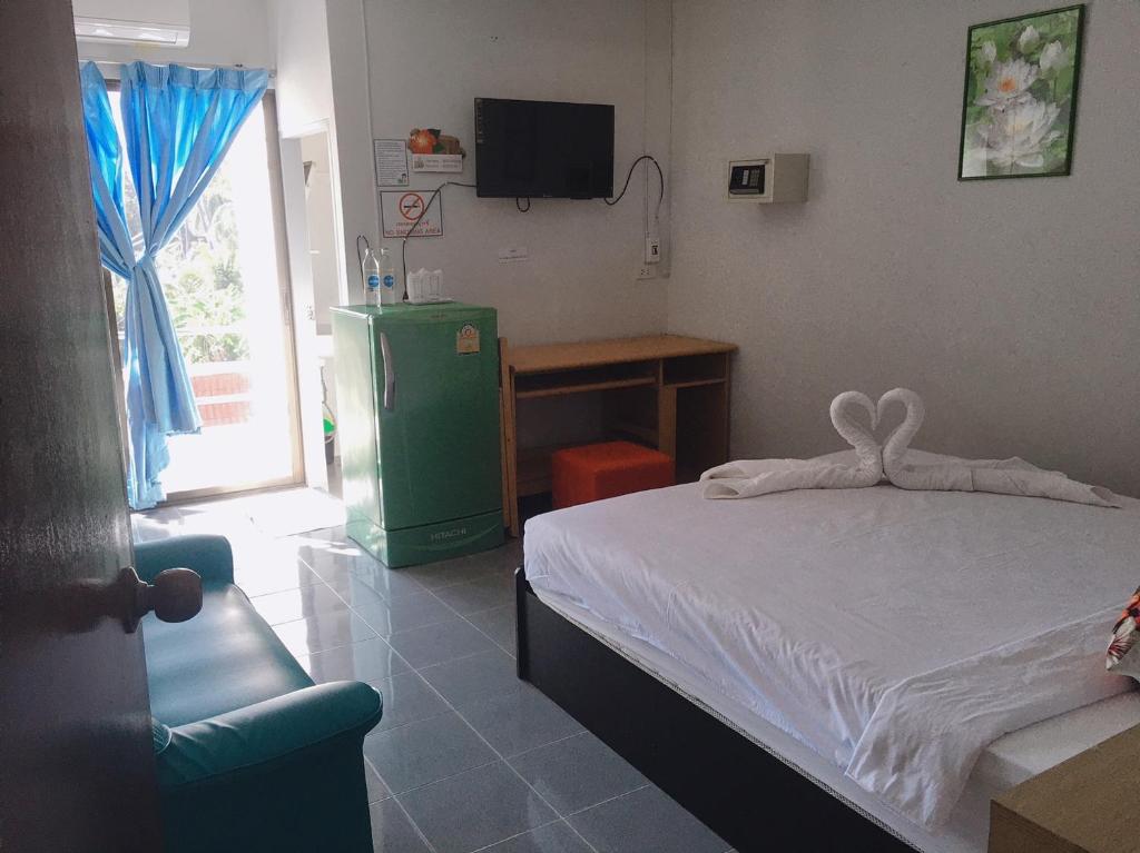 华欣华欣珍妮旅馆的一间卧室配有一张床、一台电视和一张书桌