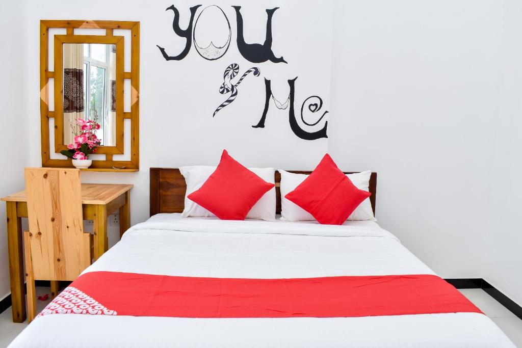亭可马里Mallika Resort的一间卧室配有红色和白色枕头的床