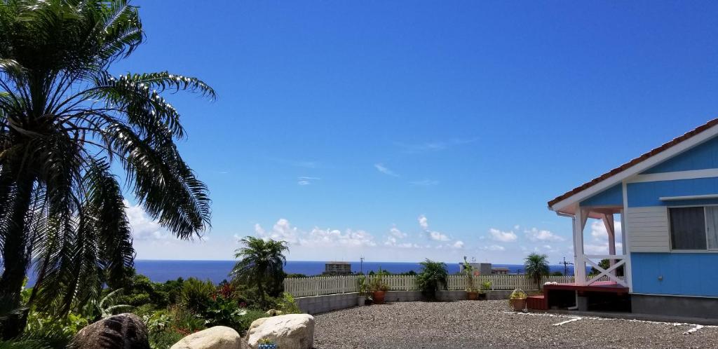 屋久岛Yakushima Pension Luana House的蓝色房子,背景是大海