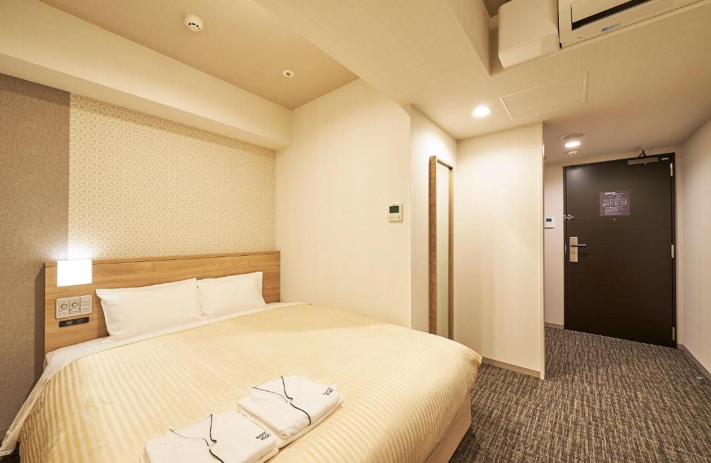名古屋Sotetsu Fresa Inn Nagoya Sakuradoriguchi的一间酒店客房,设有一张床和一扇门