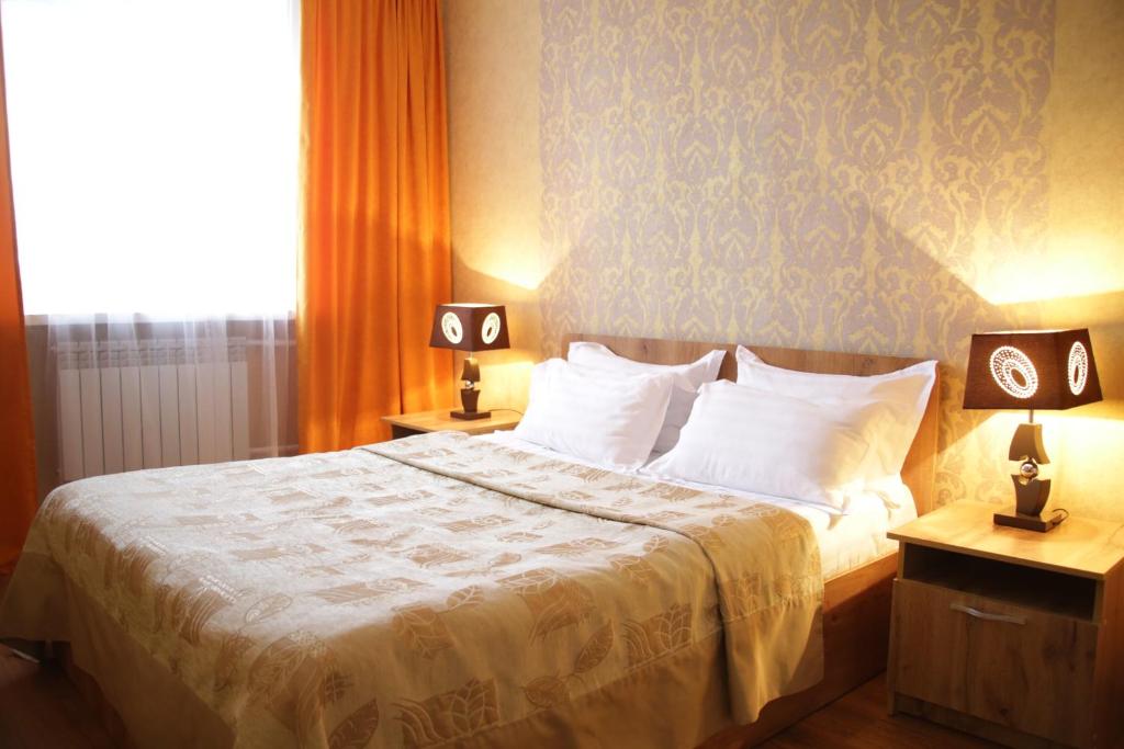 乌斯季卡缅诺戈尔斯克城市酒店的一间卧室配有一张带两张台灯的床铺。