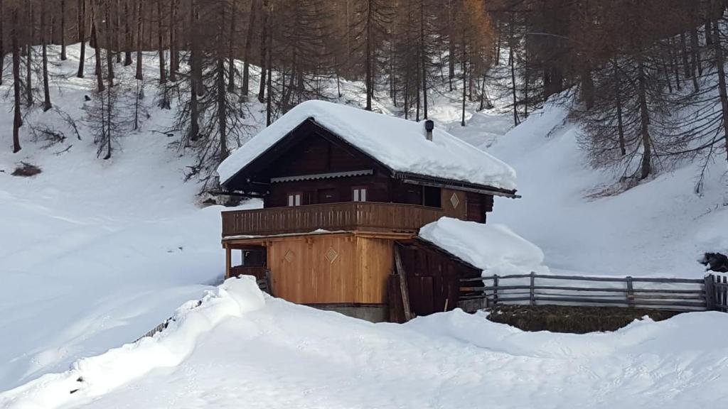 海利根布卢特Ferienhütte Ortnerkasa的雪覆盖的小小屋,设有围栏