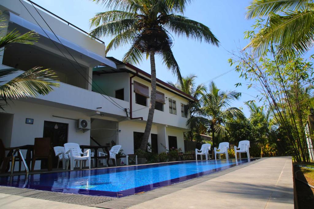 尼甘布最佳居住地住宿加早餐旅馆的一座别墅,设有游泳池和棕榈树
