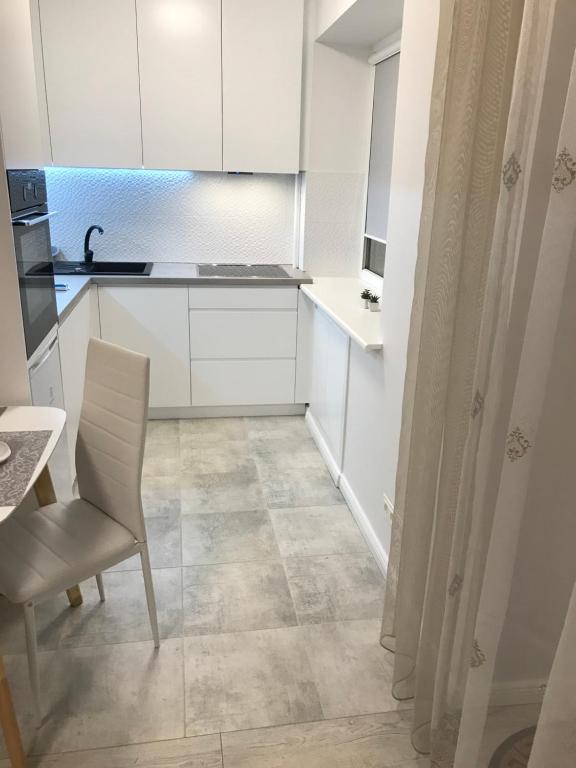希奥利艾Central Boulevard Apartment的厨房配有白色橱柜、桌子和椅子