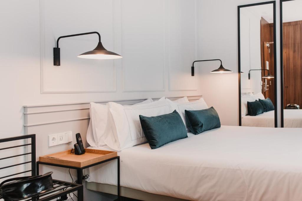 瓦伦西亚Helen Berger Boutique Hotel的卧室配有带蓝色枕头的大型白色床