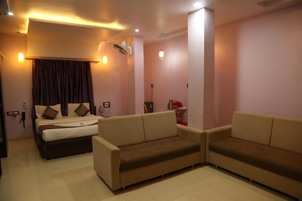 那格浦尔Hotel Sai Guest House的一间卧室配有一张床、一张沙发和一把椅子