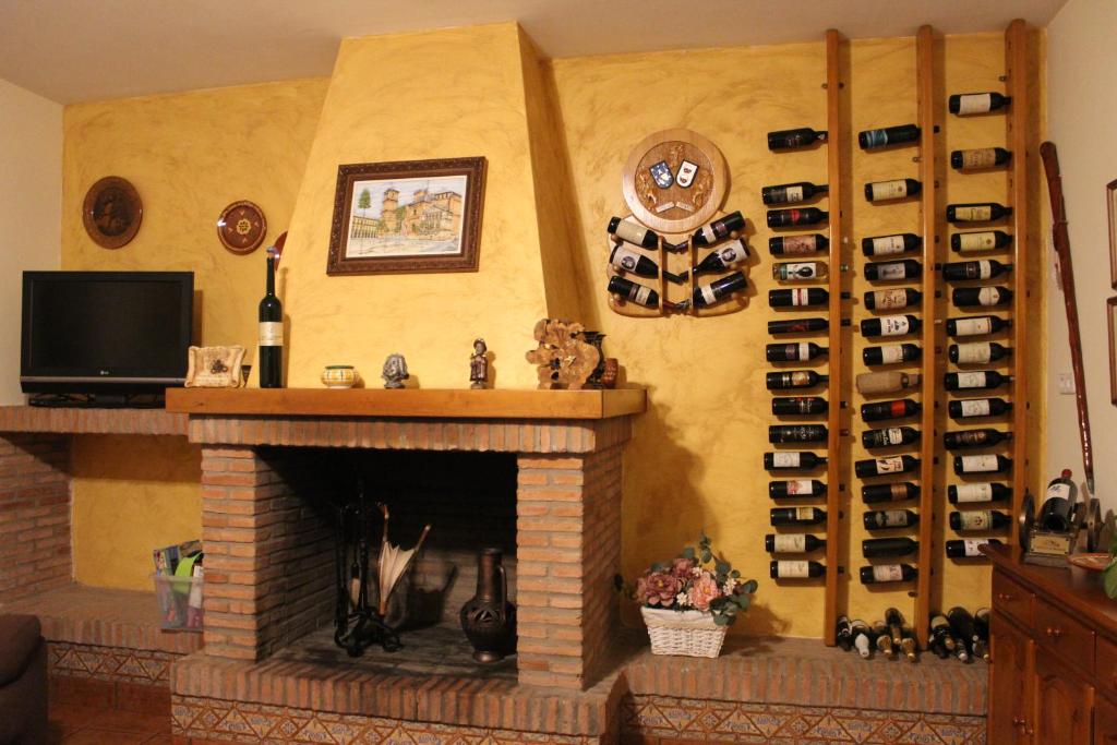 因凡特斯新镇CASA RURAL BUENA VENTURA的客厅设有壁炉,配有酒瓶架
