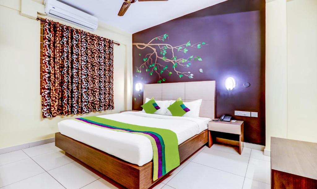 科钦Treebo Trend Petals Suites Ernakulam Town的一间卧室设有一张大床和一个窗户。