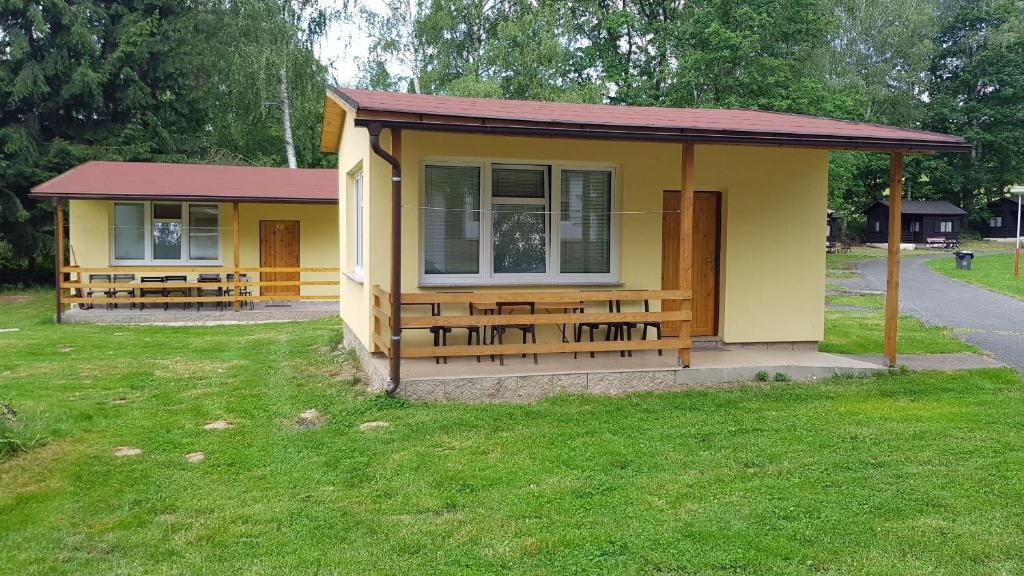 ŽandovAutocamp Slunce Žandov的院子里的黄色小房子,配有野餐桌