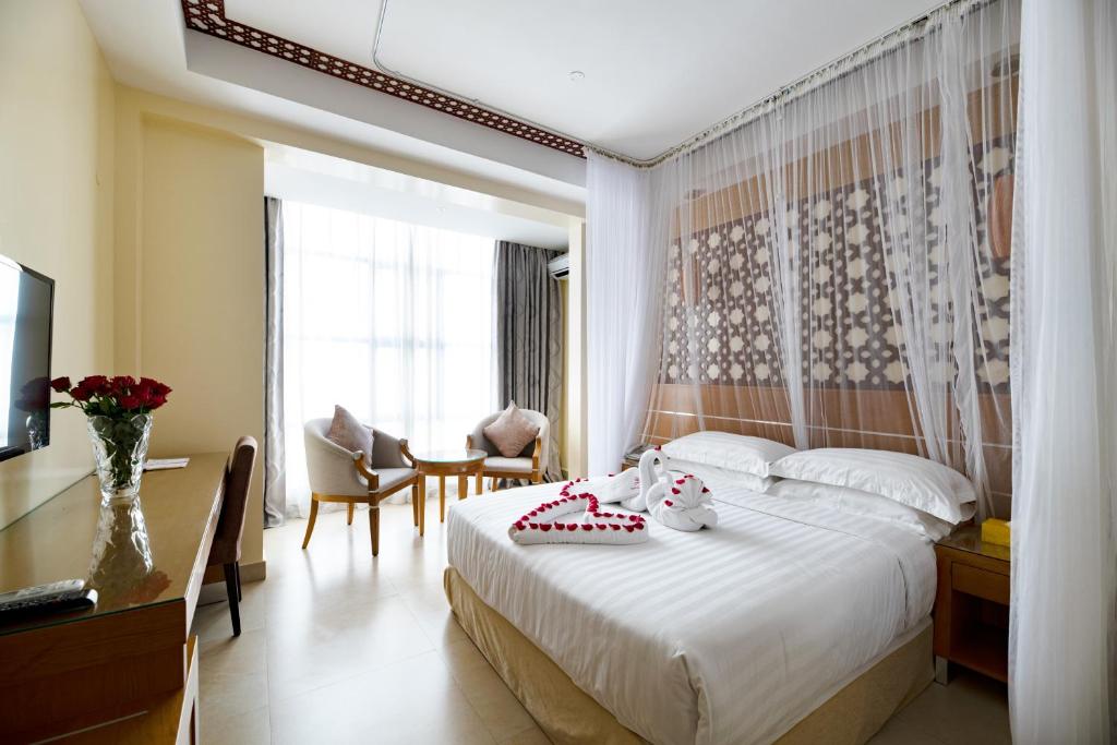 内罗毕萨博皇家酒店的一间卧室配有一张床、一张书桌和一台电视。