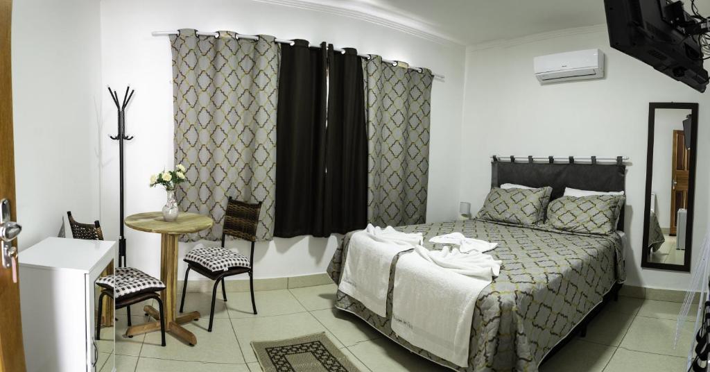 卡皮托利乌Pousada Do Alto的卧室配有一张床和一张桌子及椅子