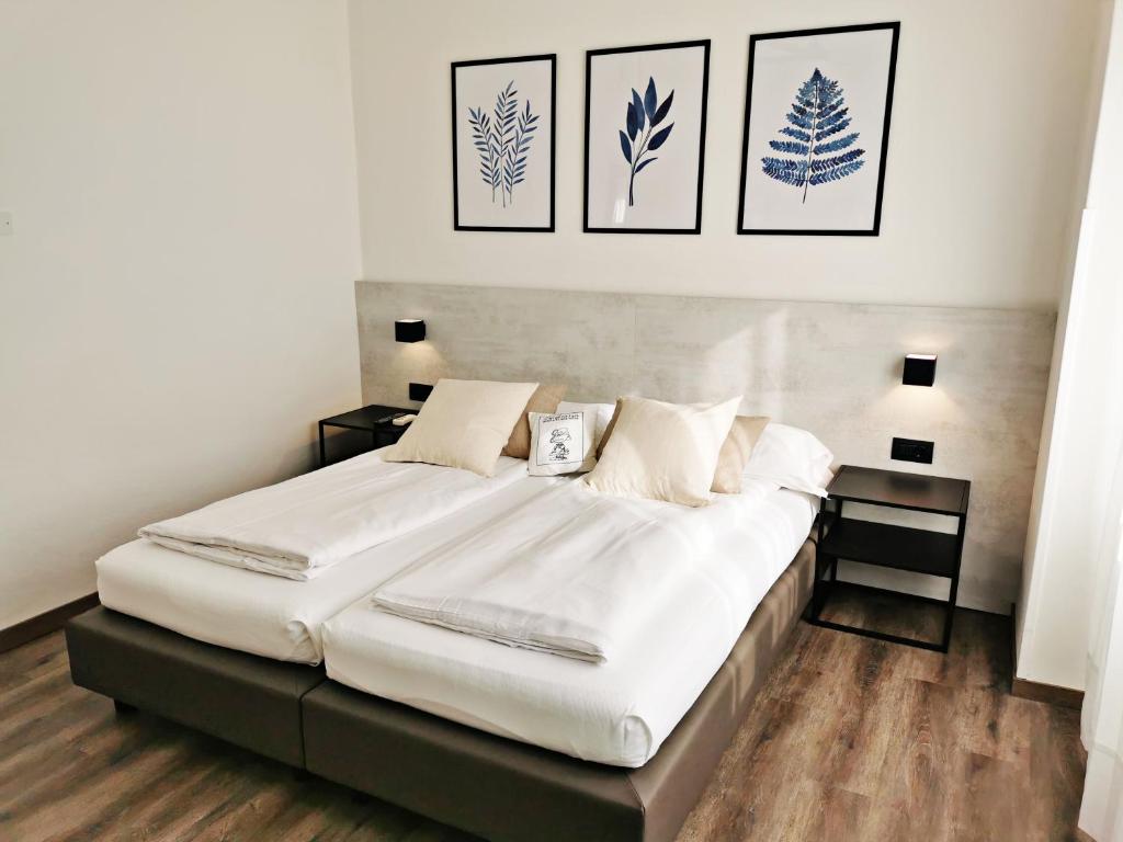 托尔博莱Villa Paola B&B的卧室配有一张白色大床,墙上挂有四张照片