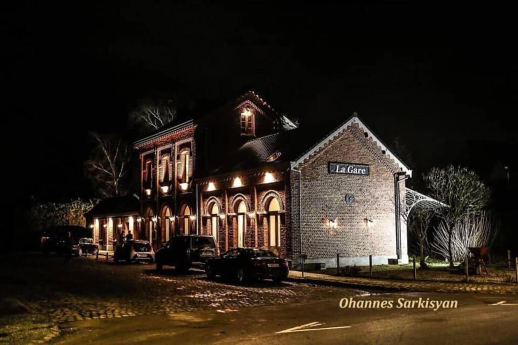 Thorembais-Saint-TrondAppartement dans un bâtiment historique的夜间有灯的建筑,汽车停在前面