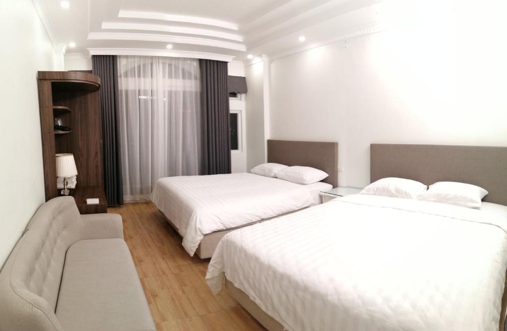 河内Roma Hotel Noi Bai airport的酒店客房,设有两张床和一张沙发