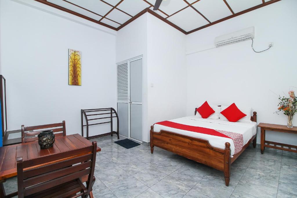 科伦坡Leo's Home Stay的一间卧室配有一张带红色枕头的床和一张书桌