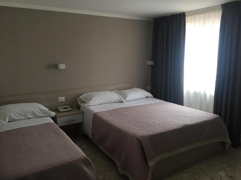 圣欧费米亚拉默齐亚Piccolo Hotel Lamezia的酒店客房设有两张床和窗户。