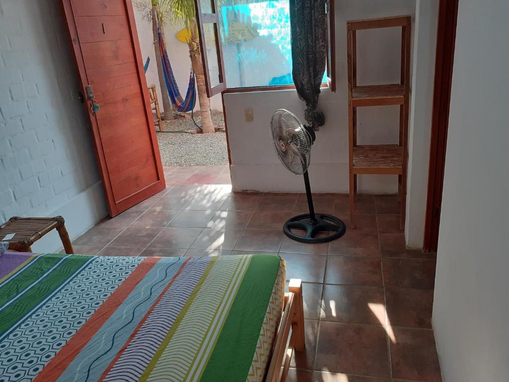 曼克拉Casa Máncora Guesthouse的一间位于地板上的客房,配有一张床和风扇