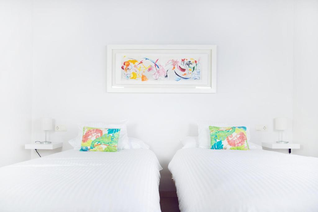 塞维利亚Hispalis Casa Palacio Apartment的白色客房的两张床,墙上挂着一幅画