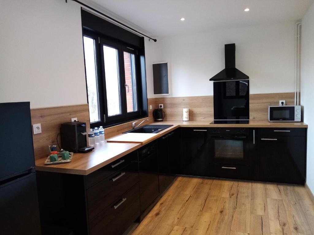 VendevilleDuplex agréable et spacieux 3 chb dont 1 communicante的厨房配有黑色橱柜、水槽和窗户。