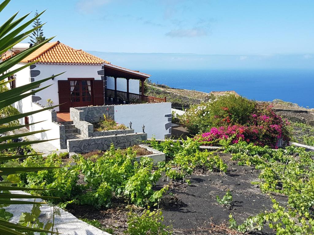 丰卡连特德拉帕尔马Casa las Las Viñas的一座房子,设有一座花园,后面是大海