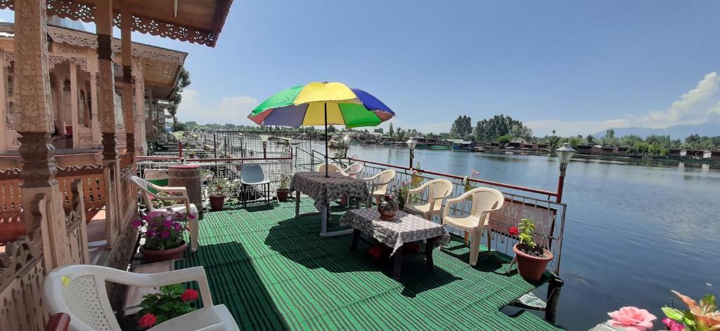 斯利那加Lake Palace Group Of House Boats的一个带桌椅的甲板和一把遮阳伞