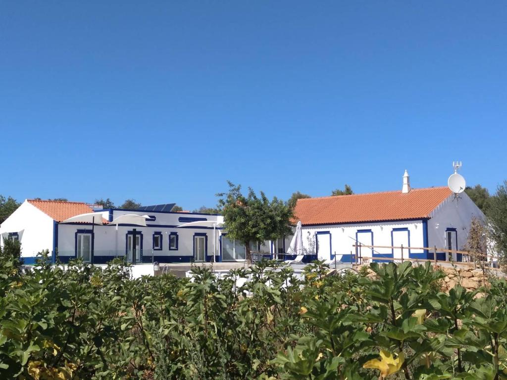 奥良Monte das Perdizes的一座白色的建筑,在田野上有一个红色的屋顶