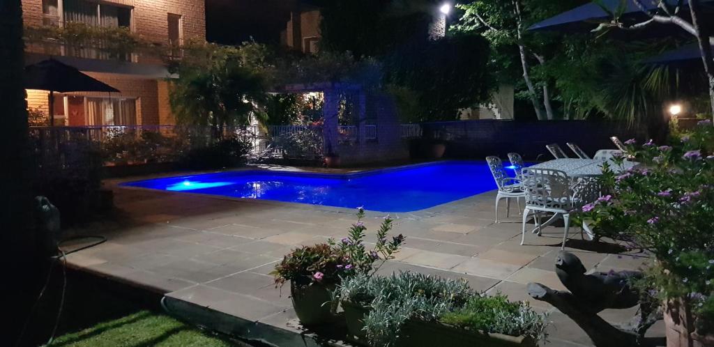豪特湾维特乐尔斯小屋酒店的后院的游泳池在晚上配有桌椅