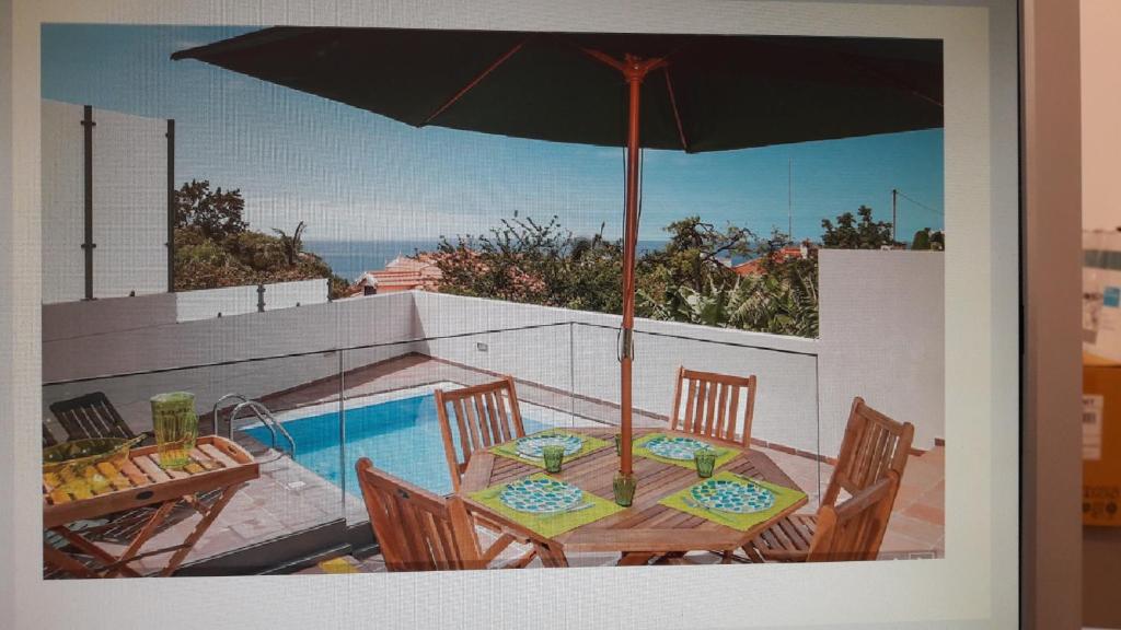 丰沙尔Casa Branca的游泳池旁带遮阳伞的桌子