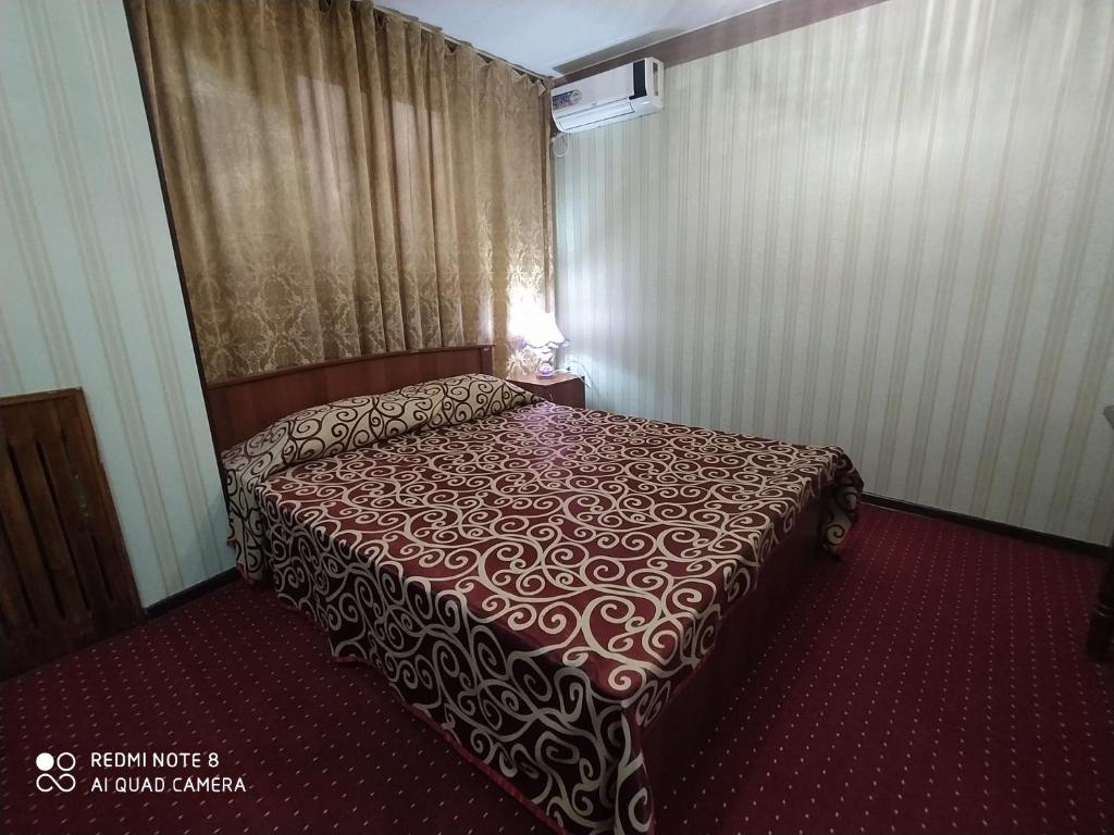 塔什干银色宾馆的酒店客房,配有一张铺有红地毯的床