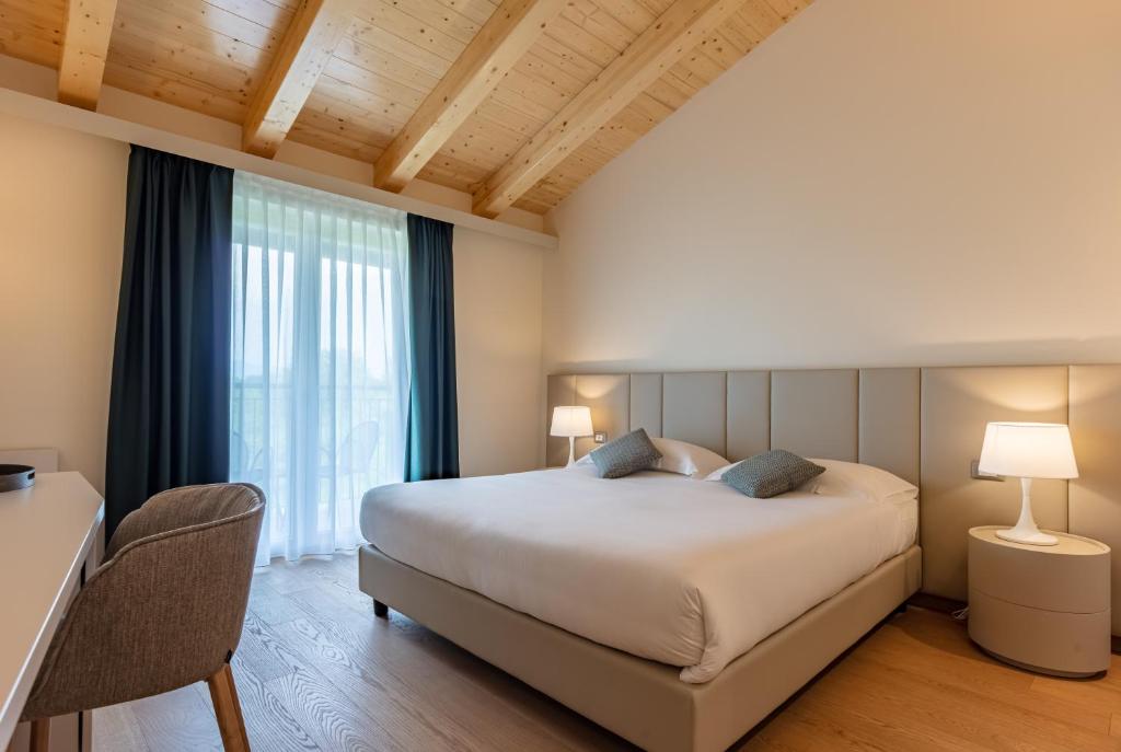 拉齐塞Leonardo Hotel Lago di Garda - Wellness and Spa的一间卧室设有一张大床和一个大窗户