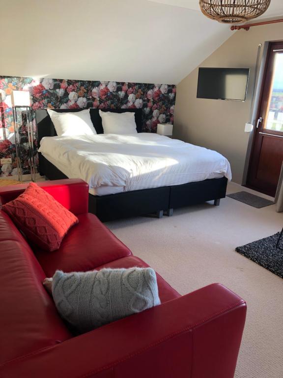 阿尔登堡De grote Zeearend的一间卧室配有一张床和一张红色的沙发