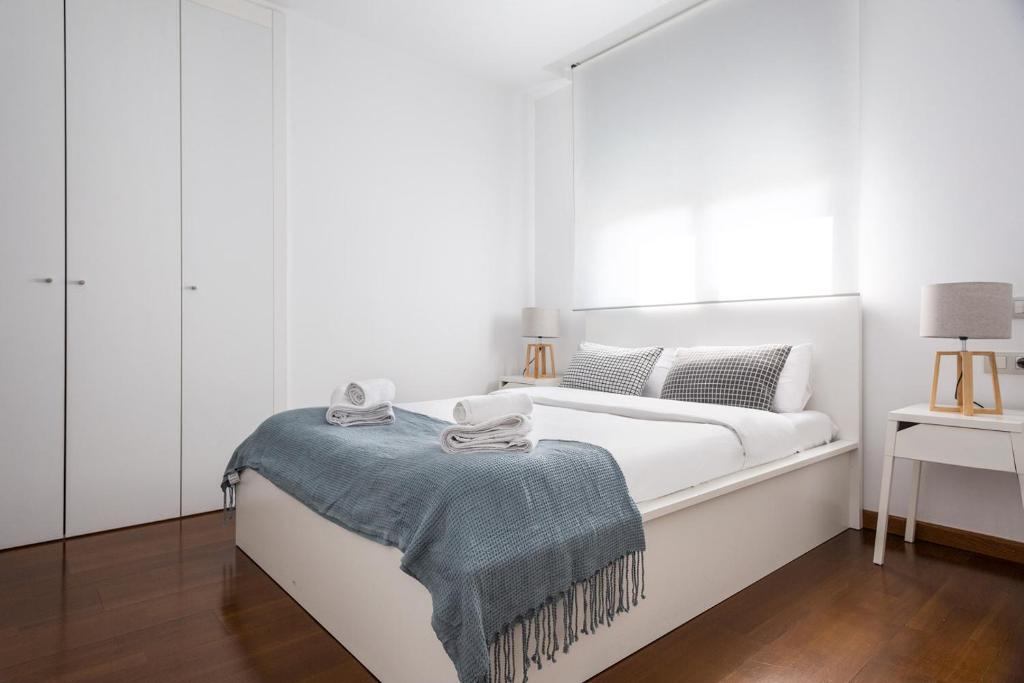 巴塞罗那Les Corts Exclusive Apartments by Olala Homes的白色卧室配有一张带蓝色毯子的床