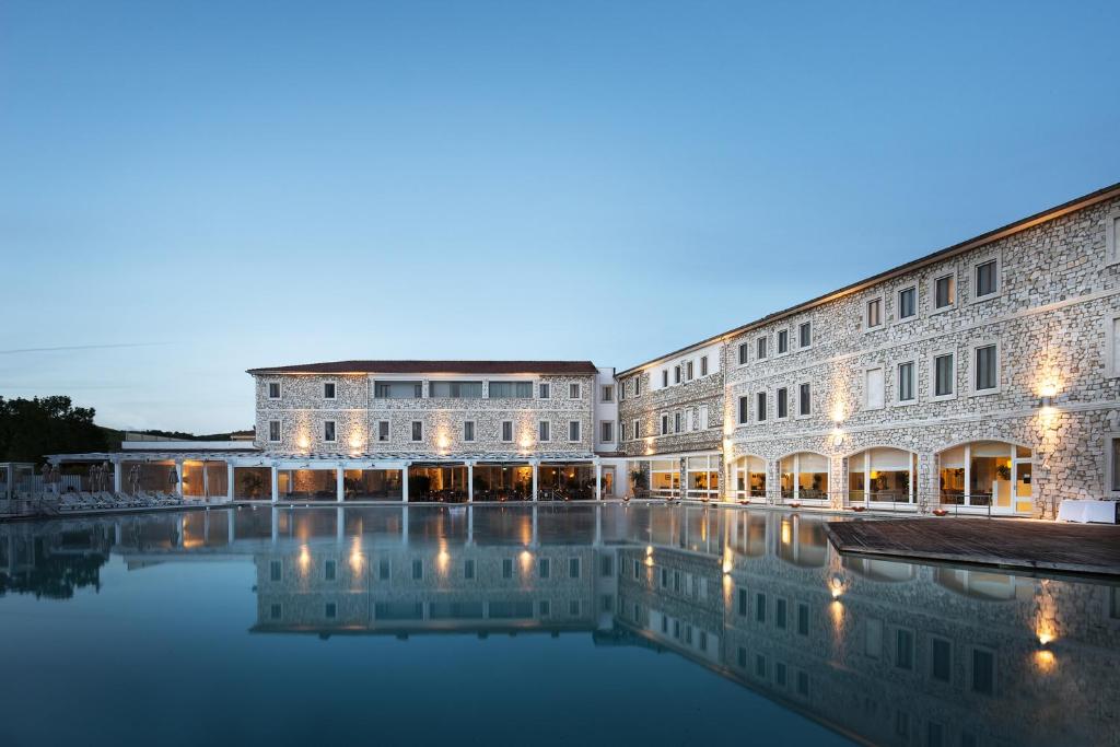 萨杜勒尼亚Terme di Saturnia Natural Spa & Golf Resort - The Leading Hotels of the World的一座建筑前面有水池