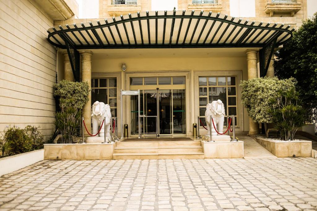 突尼斯突尼斯爱婆罗酒店的一座建筑的前门,有两座雕像
