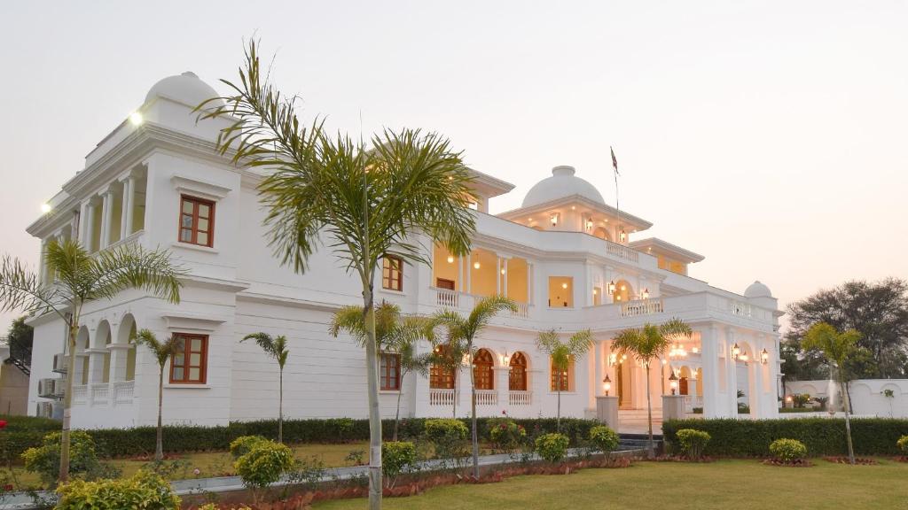 斋浦尔Umaid Farm Resort- A Legancy Vintage Stay In Jaipur的一座白色的大建筑,前面有棕榈树