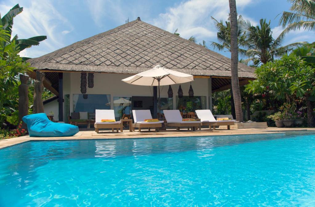TemukusVilla Paradise Lovina的一个带椅子和遮阳伞的游泳池