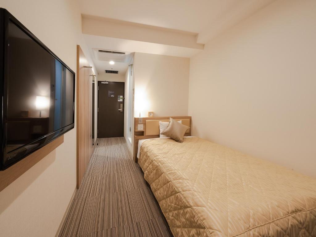 大阪UNIZO INN Osaka Kitahama的一间卧室配有一张床和一台平面电视