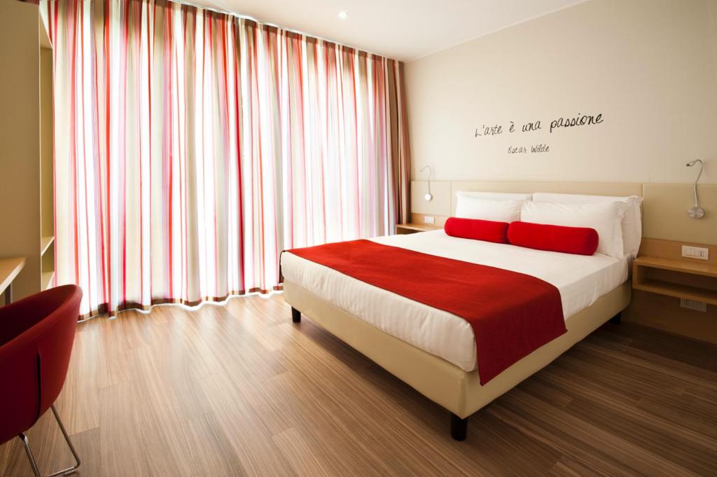 维洛尔巴UNAHOTELS Le Terrazze Treviso Hotel & Residence的一间卧室配有一张带两个红色枕头的床