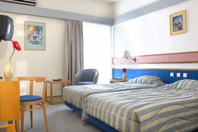 拉米亚萨马拉斯酒店的一间卧室配有一张床、一张桌子和一把椅子