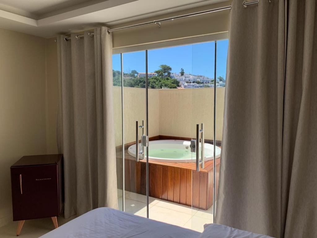 阿拉亚尔-杜卡布Pousada Arraial Tropical的卧室设有带浴缸的大窗户