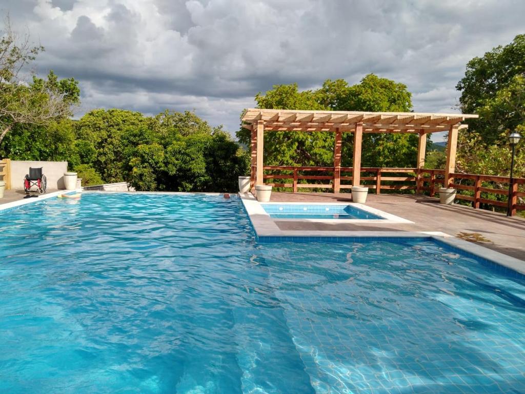 戈亚斯Pousada Portalcion的一个带木制凉棚的大型游泳池和一个游泳池