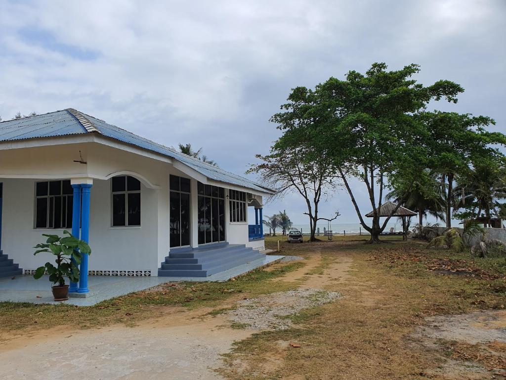 哥打巴鲁ALA Beach Lodge - Ketapang Homestay的白色的房子,有蓝色的修剪和一棵树