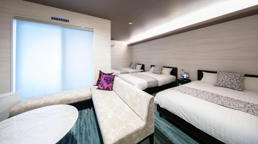 高松GRAND BASE Takamatsu的客房设有三张床、一张沙发和一个窗口。