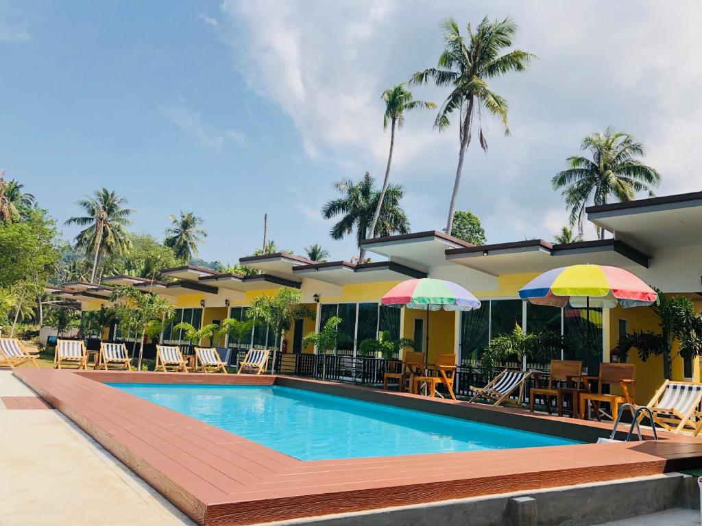 达叻府Koh Chang Havana Pool Villa的度假村的游泳池,配有椅子和遮阳伞