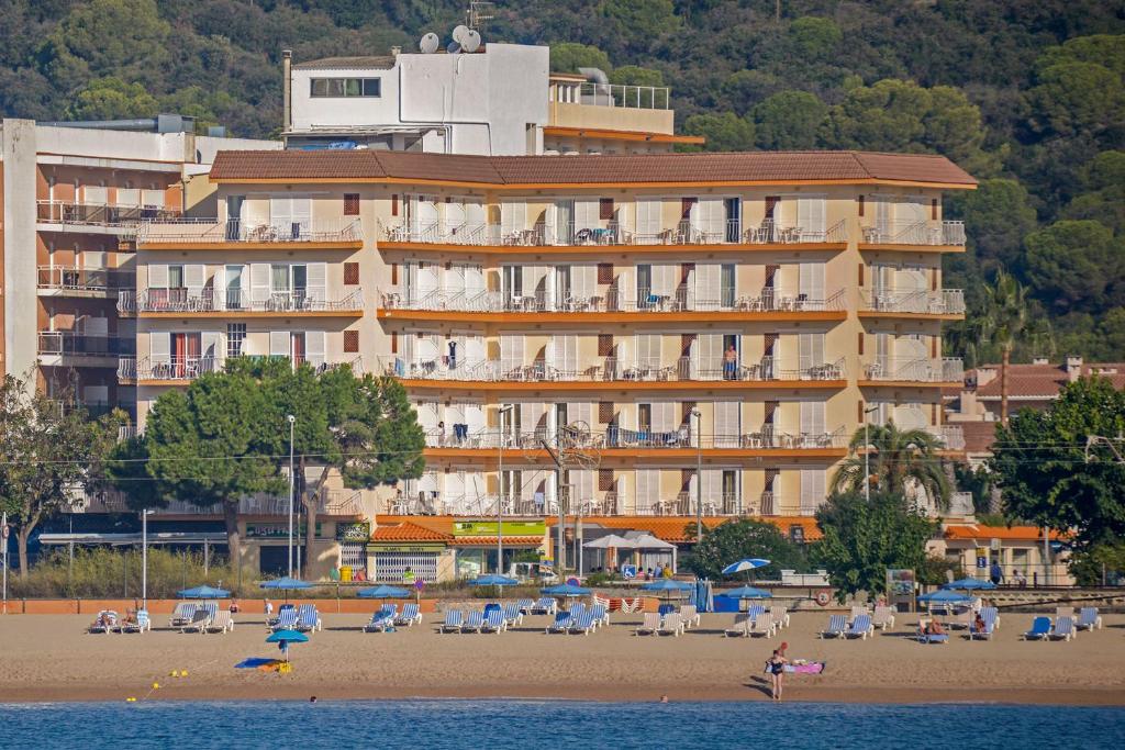 马尔格莱特德玛Hotel Rosa Nàutica的海滩上一座大型建筑,配有椅子和人