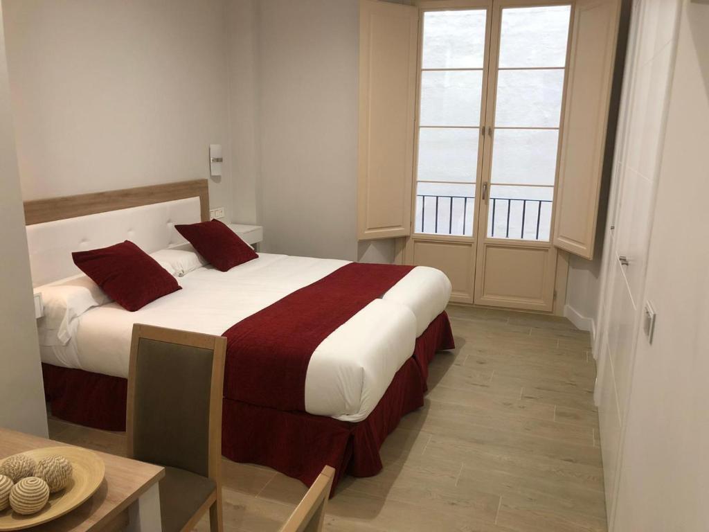 马拉加Pinar Malaga Rooms的一间卧室配有一张带红色枕头的大床