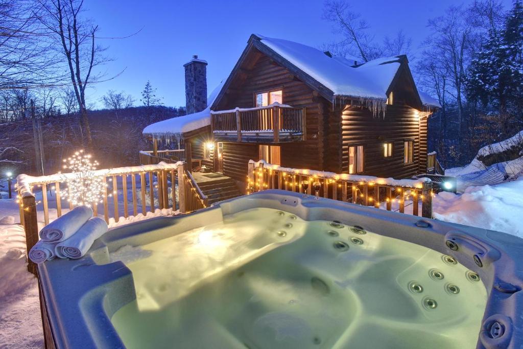 LabelleChic Familiale, Relaxant avec spa en montagnes的雪地小木屋前的热水浴池