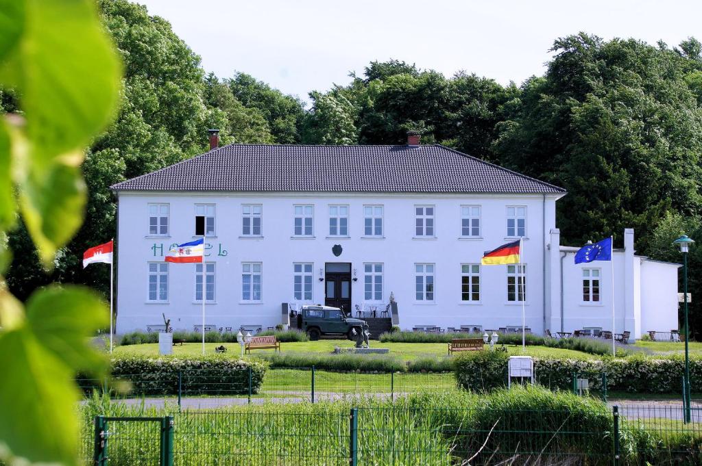 Klein StrömkendorfOstsee-Gutshaus Am Salzhaff Pepelow nähe Rerik- am Meer residieren!的前面有旗帜的大型白色建筑