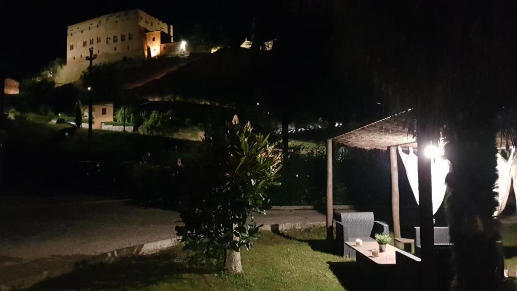 蒙塔尔奇诺VAL D'ORCIA DELUXE 2, RAFFINATA CASA immersa nel verde con WiFi, giardino e parcheggio的享有带桌子和树的建筑的夜景